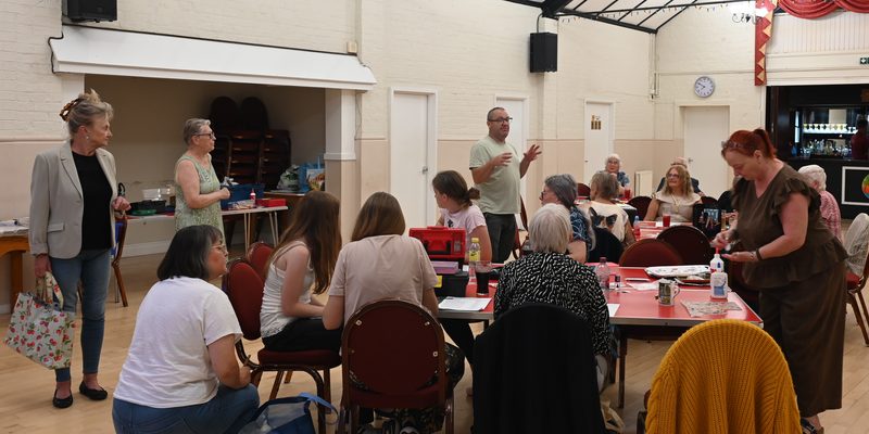 The Dolls House Club meeting in the Main Hall, members at work around the tables